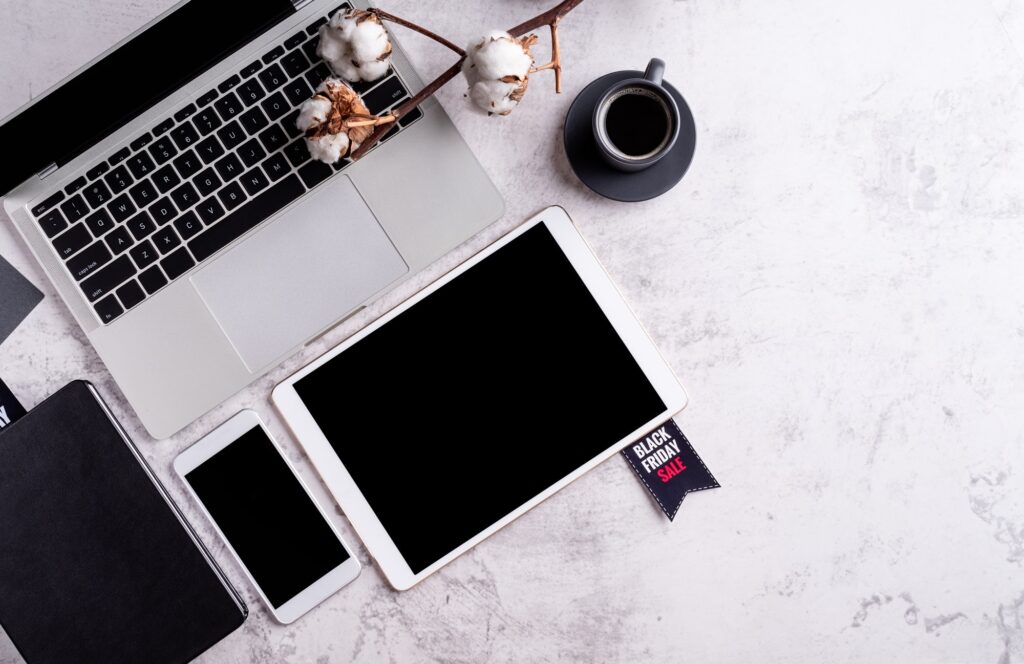 Black Friday Sale words on the tag, workspace with laptop, tablet and smartphone top view flat lay
