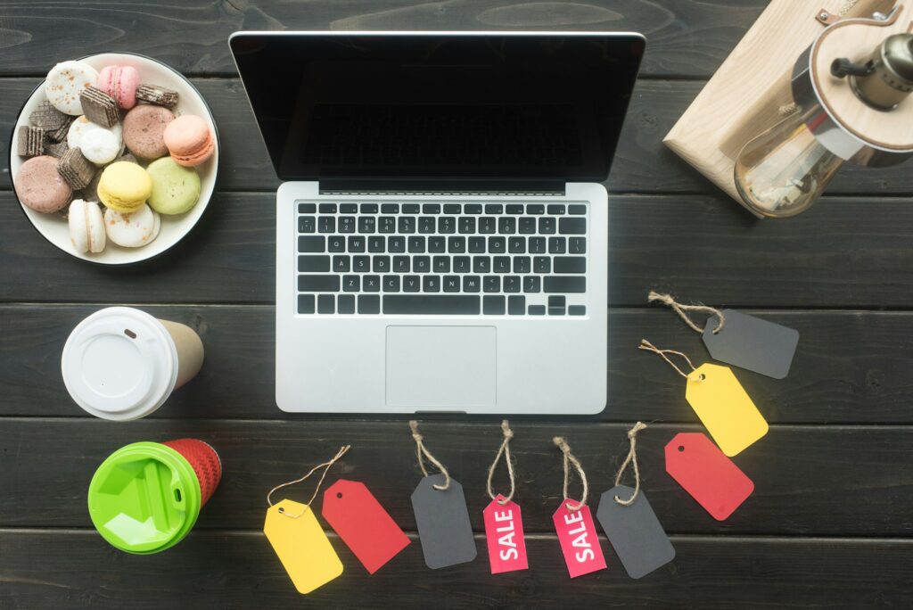 top view of laptop on table with macarons, coffee and sale tags